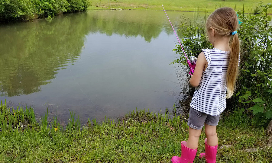 Young girl fishing by the pond